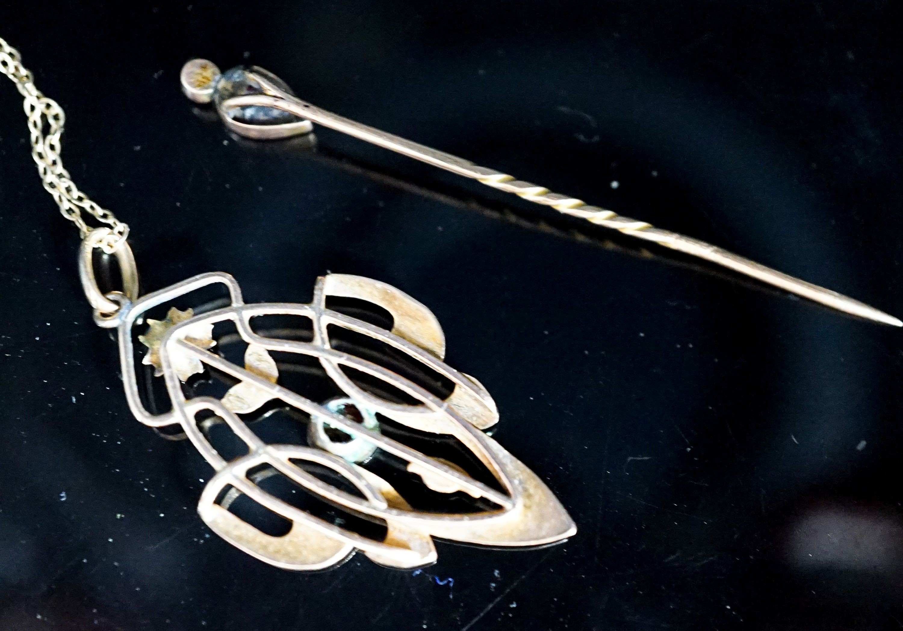 An Art Nouveau yellow metal and garnet set pendant,39mm, on a 9ct chain and a garnet and split pearl set stick pin, gross weight 5.8 grams.